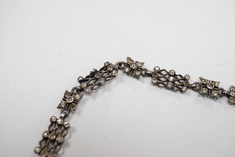 An early 20th century white metal and white paste set cluster necklace, each trellis style link mounted with nine paste stones, approx. 38cm.